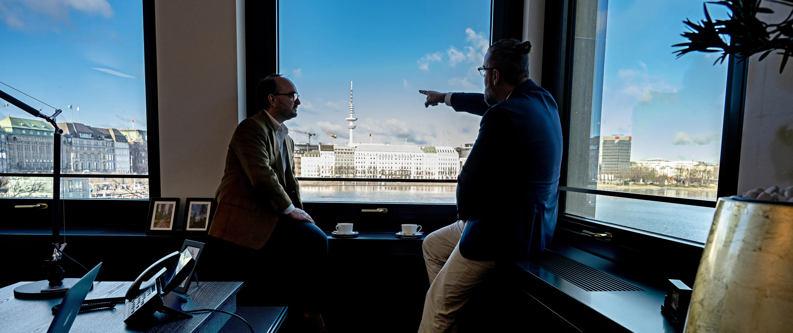 Zwei Berater im Gespräch am Fenster mit Blick auf die Hamburger Binnenalster